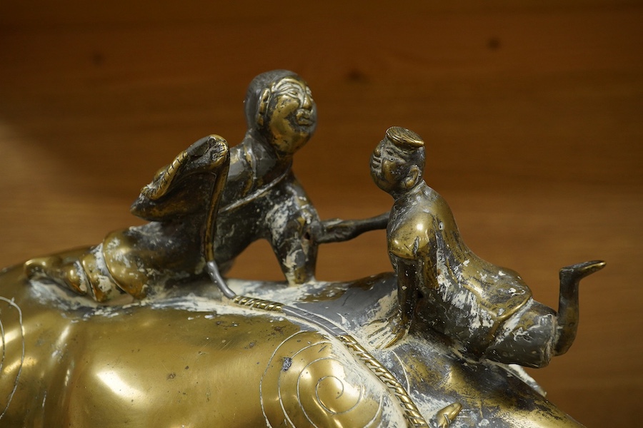 A Chinese bronze and lead model of an ox with two riders, 25cm high. Condition - fair